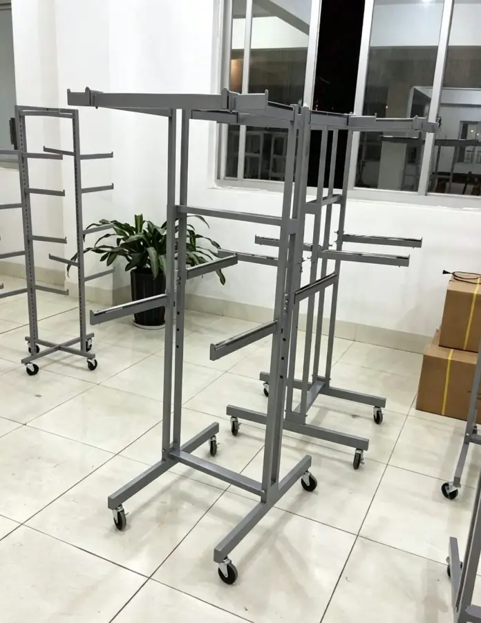 Multiple mobile garment display racks with multi-tier extending hanging arms in showroom staging area
